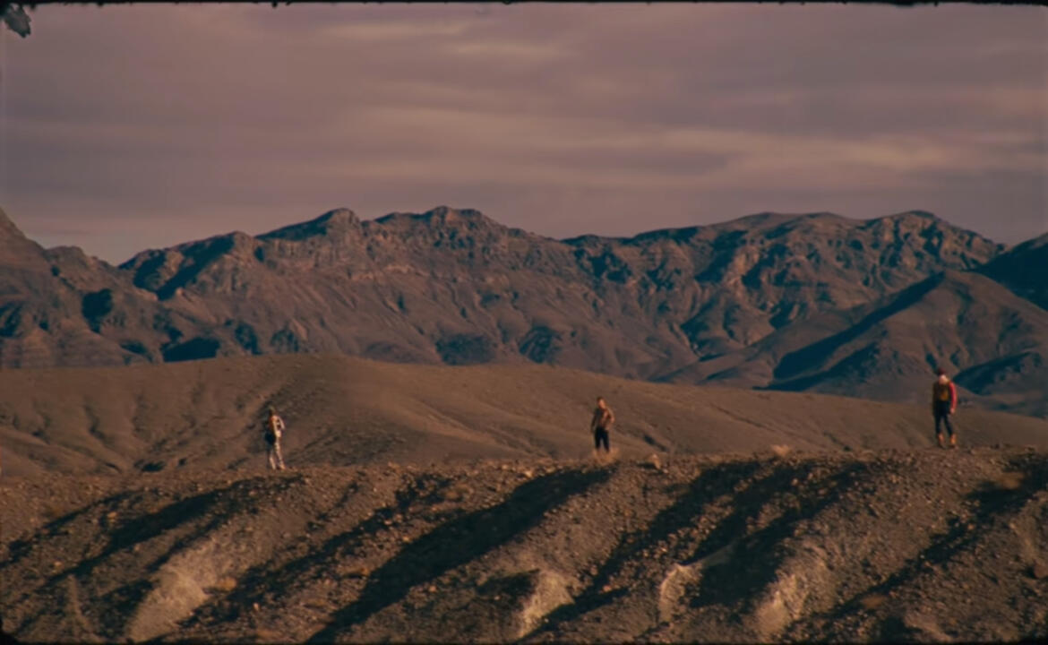Three cowboys on a rose-tinted mountain landscape